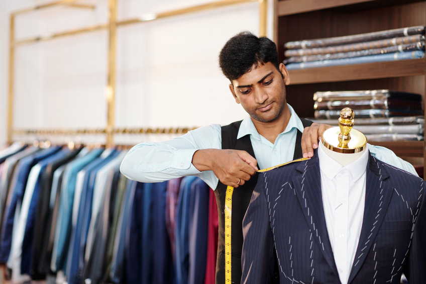 tailor taking measurements of bespoke suit jacket on mannequin