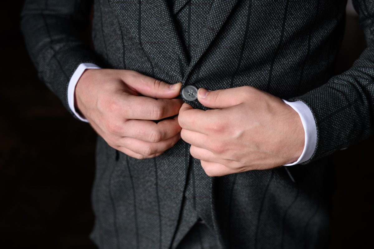 Portrait of a fashionable man buttoning a button on his jacket, close-up.Concept of men's fashion,wedding day.